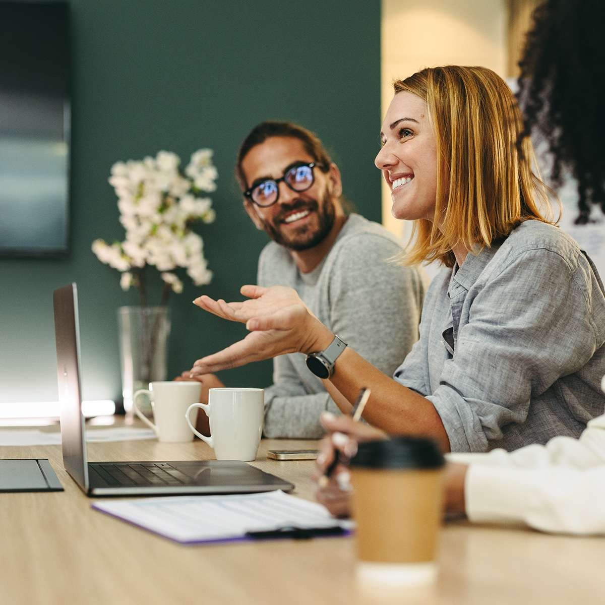 individuals at a meeting with laptops and coffee